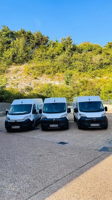 Three delivery vans parked front-on under a clear sky