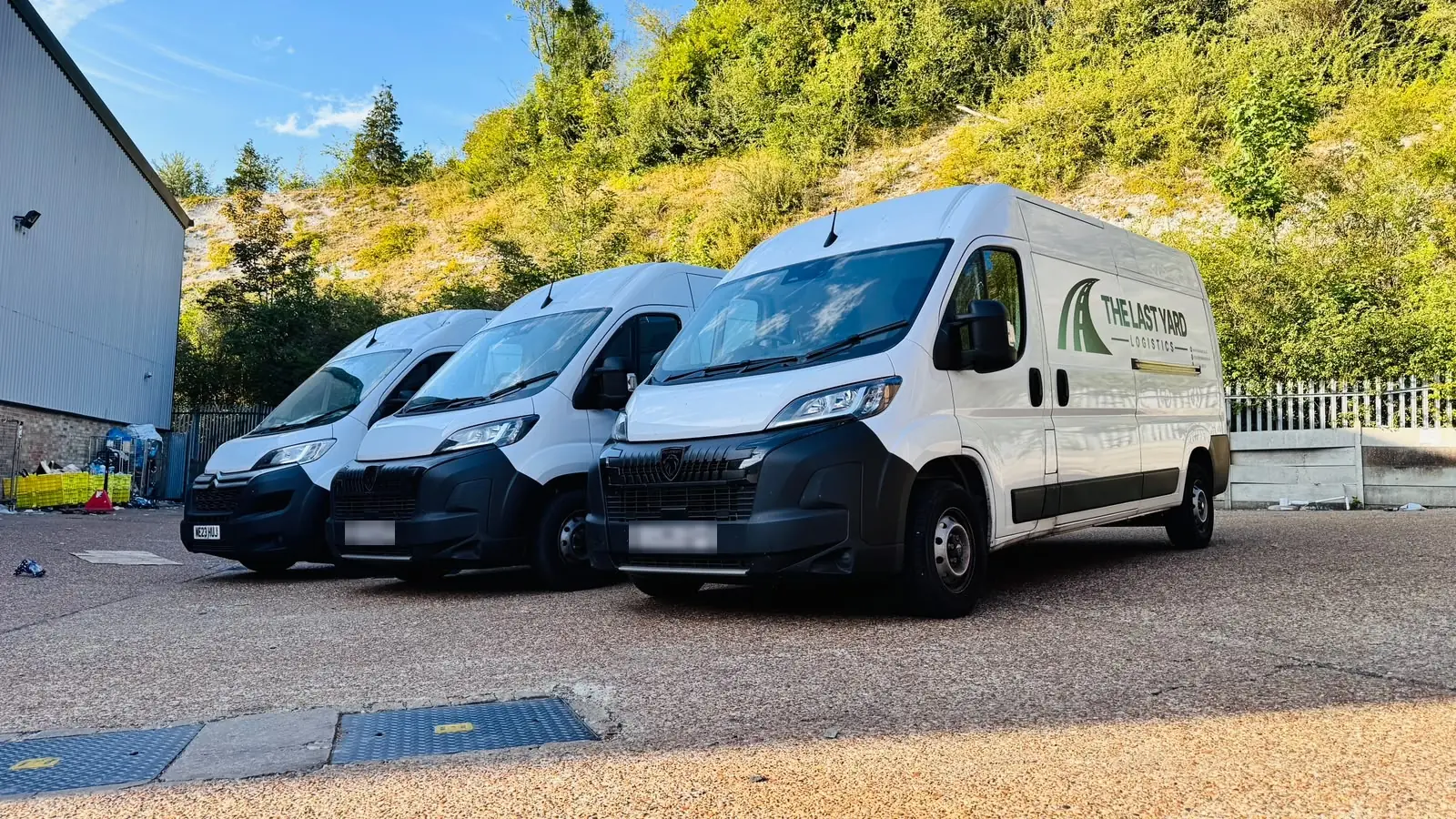 Three liveried The Last Yard Logistics Peugeot Boxer and Citroën Relay vans parked at the depot
